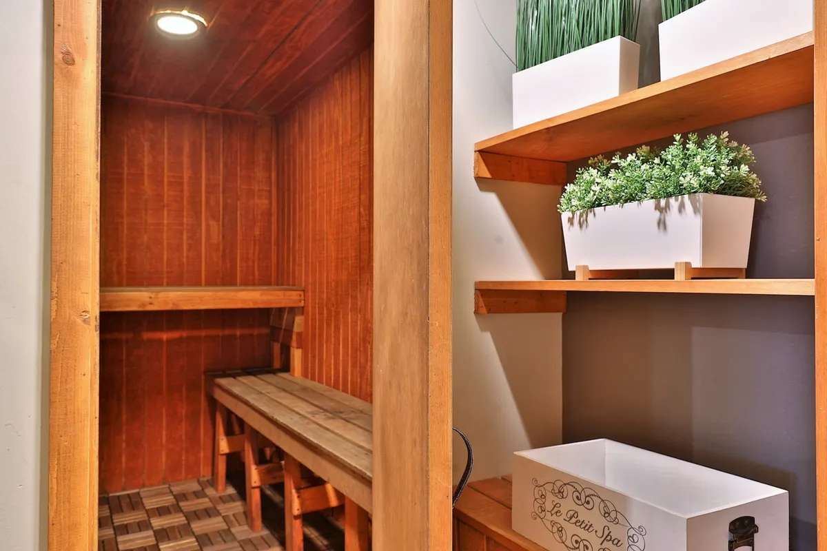 A tranquil sauna room with wooden benches and shelves adorned with potted plants. The lighting and ambiance evoke relaxation and rejuvenation, making it ideal for unwinding after a day of activities.