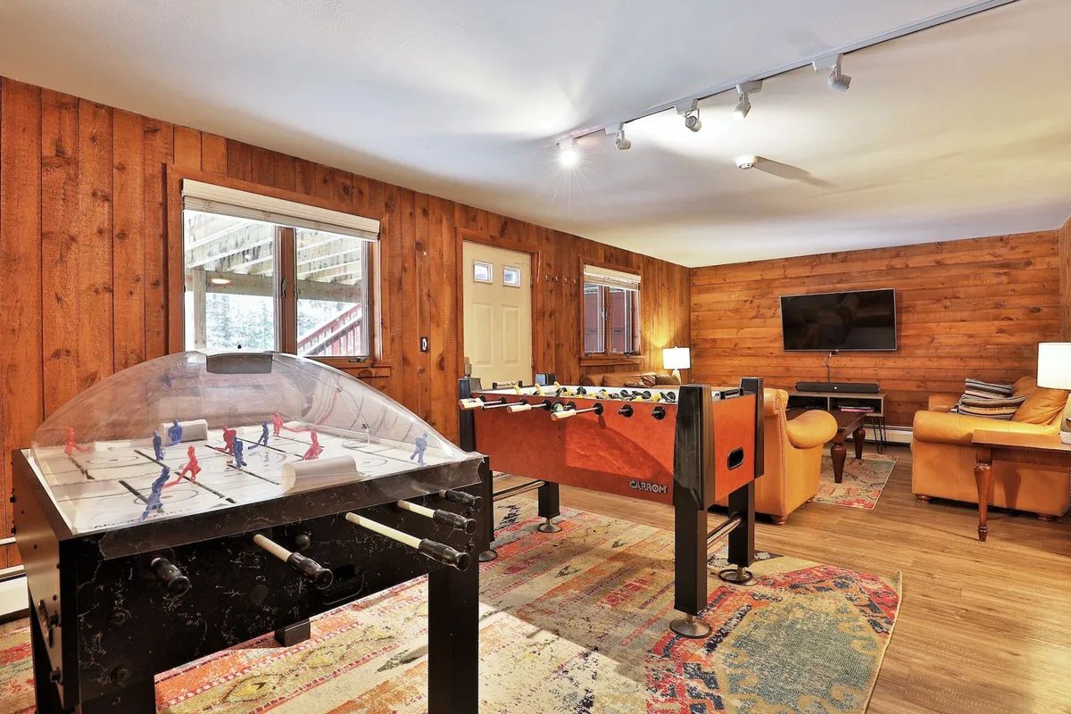 A lively interior space featuring a foosball table, air hockey table, comfortable seating, and television. The room radiates a fun and casual atmosphere perfect for group activities, games, and movie watching.