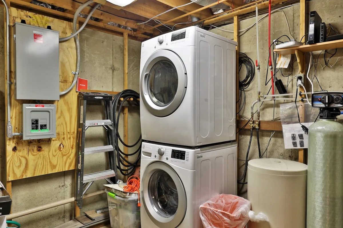 This practical image highlights the stacked washer and dryer, storage shelves, and a circuit breaker panel, emphasizing organized storage and convenience. It evokes the sense of a well-equipped interior, suitable for storing gear and managing household needs.